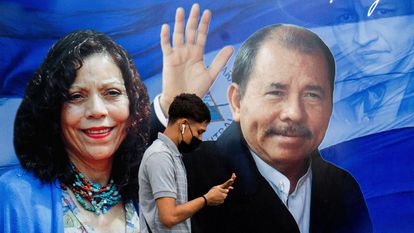 Um homem verifica seu telefone enquanto passa por cartaz promovendo o presidente Daniel Ortega e a vice-presidenta Rosario Murillo em 25 de setembro.