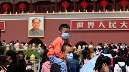 Homem carrega uma criança usando máscaras na visita à Cidade Proibida, em Pequim.