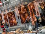 Pedestrians are reflected in the storefront window of a Chinese restaurant displaying roasted duck in downtown Lima, Peru, Saturday, July 11, 2020, amid the new coronavirus pandemic. (AP Photo/Rodrigo Abd)