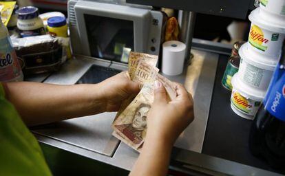Operadora de caixa conta dinheiro em um supermercado de Caracas.