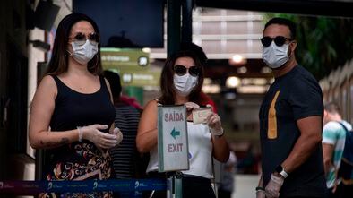Tourists wears face masks after buying tickets at the Corcovado hill train station, to go up to see the statue of Christ the Redeemer in Rio de Janeiro, Brazil, on March 17, 2020. - Rio de Janeiro's state government closed the iconic Christ the Redeemer statue and the cable car to Sugarloaf Mountain, two of the city's most famous attractions, as an emergency measure to stop the spread of the new coronavirus COVID-19. (Photo by MAURO PIMENTEL / AFP)