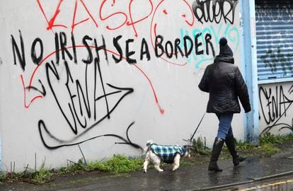 Uma mulher passa diante de um muro de Belfast onde se lê: "Sem fronteiras no mar da Irlanda", nesta quarta-feira.