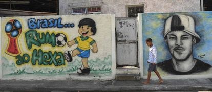 Menino caminha diante de grafites sobre a Copa no Rio.