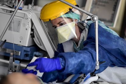 Equipe médica vestida com equipamento de proteção individual (EPI) cuida de um paciente na unidade de terapia intensiva na Bélgica.