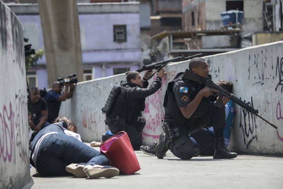 Moradores tentam se proteger de tiroteio em passarela da Rocinha enquanto policiais trocam tiros com traficantes no Rio.