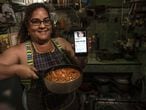 Yuliet Colón posa con la comida que preparó y su teléfono con su página de cocina de Facebook en su casa en La Habana, Cuba, el 2 de abril.