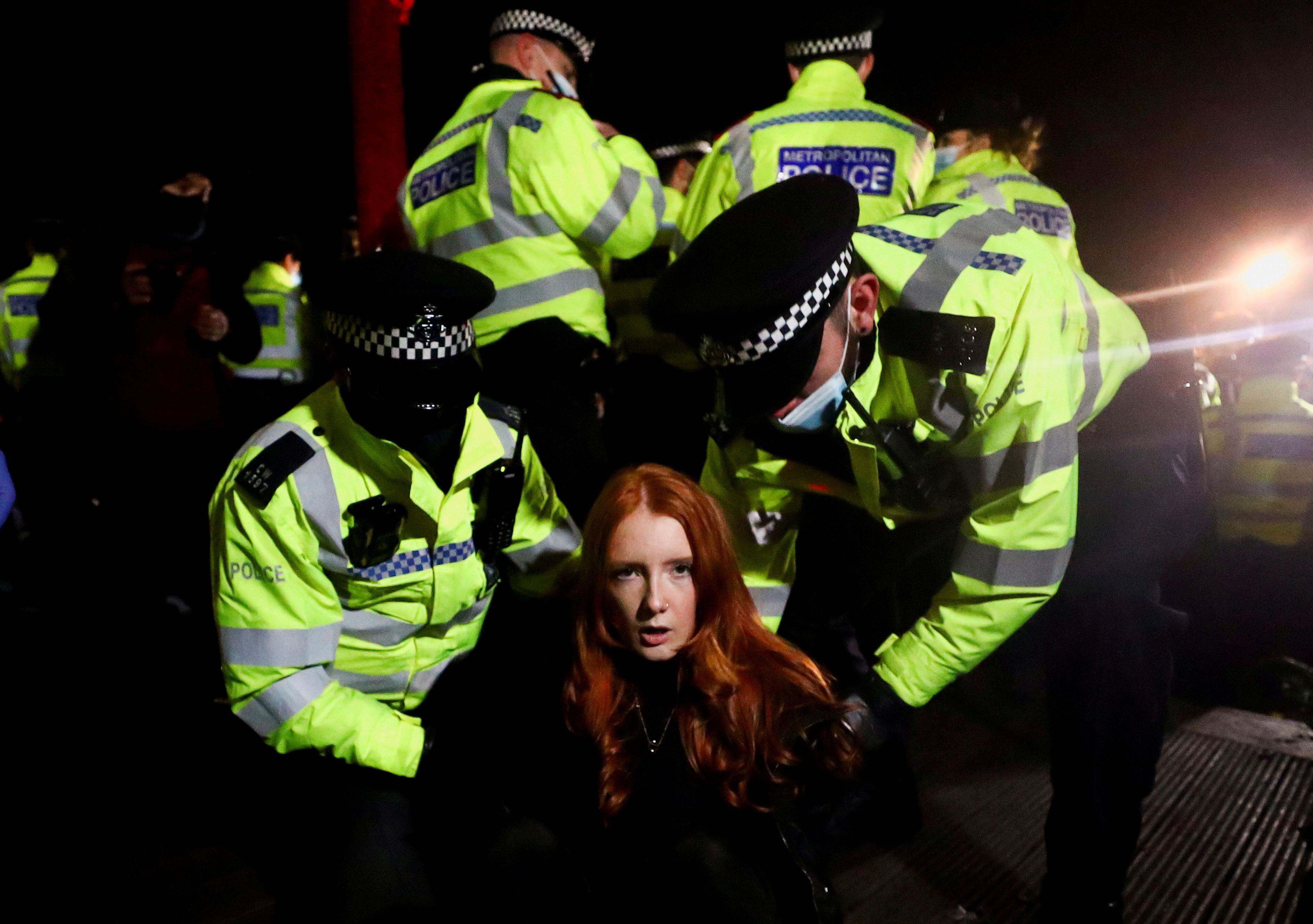 Agentes da Scotland Yard detém uma mulher no sábado, durante uma vigília, em Londres. 