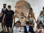 People wearing face masks to protect against coronavirus walk through the subway, with a portrait of Soviet founder Vladimir Lenin in the background, in Moscow, Russia, Wednesday, June 10, 2020. Moscow residents are no longer required to stay at home or obtain electronic passes for traveling around the city. All restrictions on taking walks, using public transportation or driving have been lifted as well. (AP Photo/Pavel Golovkin)