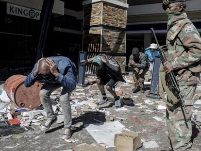Militar vigia homens detidos por saque em um centro comercial de Soweto no dia 13.