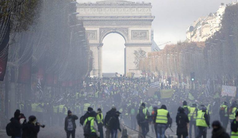 Uma nuvem de gás envolve os manifestantes, que levantaram barricadas na avenida Champs Élysées.