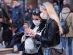 Dos mujeres consultan el móvil protegidas del coronavirus con mascarillas, en la Piazza della Rotonda (Roma).