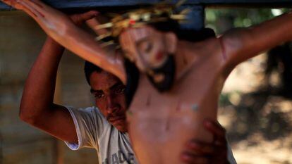 Homem carrega estátua de Jesus Cristo antes de procissão em El Salvador.