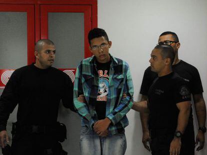 O suspeito Caio Silva de Souza (centro) na sede da pol&iacute;cia do Rio.