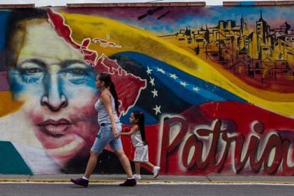Mulher caminha em frente a um mural de Chávez.