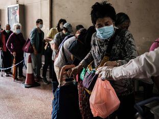 Pessoas fazem fila para pegar refeição doada em Hong Kong.