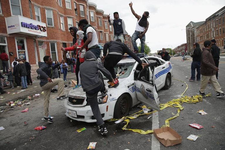 Manifestantes de Baltimore destroem um carro de polícia.