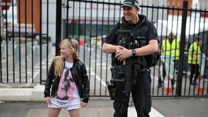 Menina posa com um policial antes do show de Ariana Grande em Manchester, neste domingo.