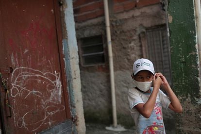 Criança ajusta máscara na favela de Paraisópolis, em São Paulo.