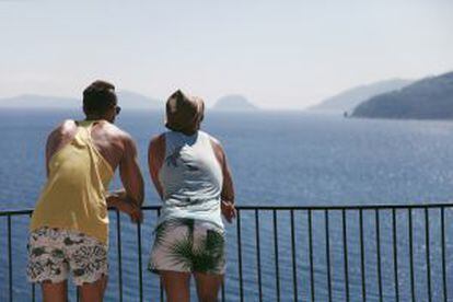 Dois turistas contemplam o mar na ilha grega de Skiathos.