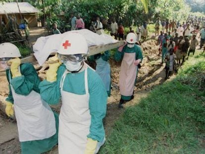 Membros da Cruz Vermelha transportam o cadáver de uma vítima de ebola, em 1995, perto de Kikwit, no Zaire.