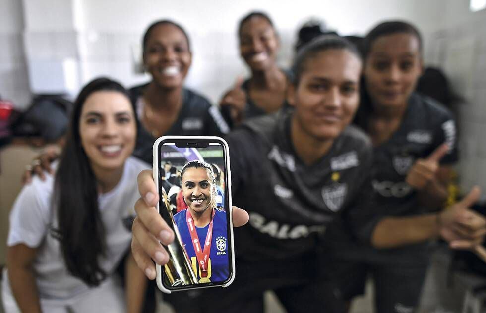 Jogadoras do Atlético Mineiro mostram uma foto de Marta