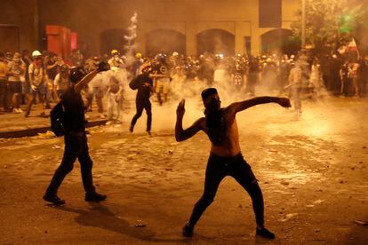 Um manifestante joga pedras contra a polícia antidistúrbios libanesa, em Beirute. Em vídeo, nova jornada de confrontos em Beirute.