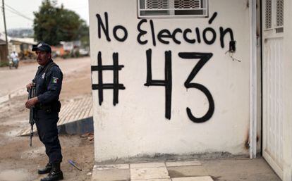 Policial em Guerrero (México) ao lado de pichação pelo boicote eleitoral.