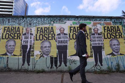 Homem passa diante de cartazes do ministro da Economia, Paulo Guedes, em São Paulo no dia 30 de agosto.