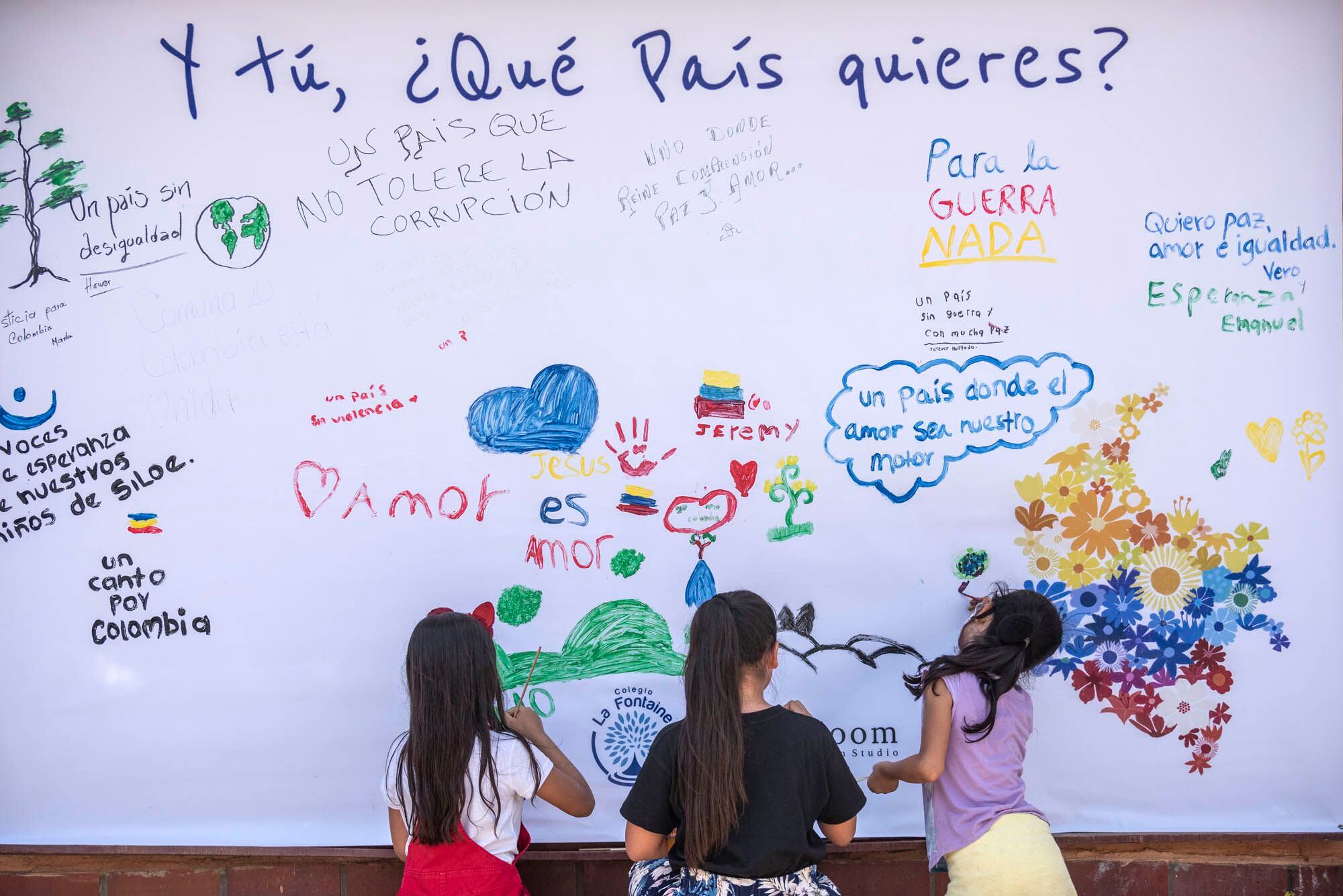 Crianças de um colégio do bairro Siloé (Cali) escrevem frases em um muro. 