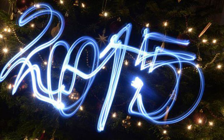 2015 escrito com lanternas de led em frente a árvore de Natal.