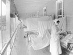 FILE - In this November 1918 photo made available by the Library of Congress, a nurse takes the pulse of a patient in the influenza ward of the Walter Reed hospital in Washington. For President Woodrow Wilson, the pandemic was a case of first impression. The country was accustomed to 100,000 deaths a year from the flu. Widespread use of vaccines were not common. It wasn't that Wilson was restrained about using federal power, he simply had far less precedent to lean on, and a much higher priority in the war effort.  (Harris & Ewing/Library of Congress via AP, File)
