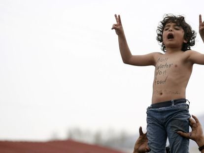 Uma criança protesta na fronteira entre Grécia e Macedonia pela falta de água e alimentos. "Nem água nem comida", diz o eslogan pintado no peito.