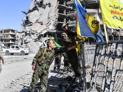 Membros das Forças Sírias Democráticas colocam sua bandeira na praça A o-Naim em Raqa nesta terça-feira.