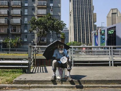 Um homem pede esmola sentado na avenida Libertador, na capital da Venezuela.