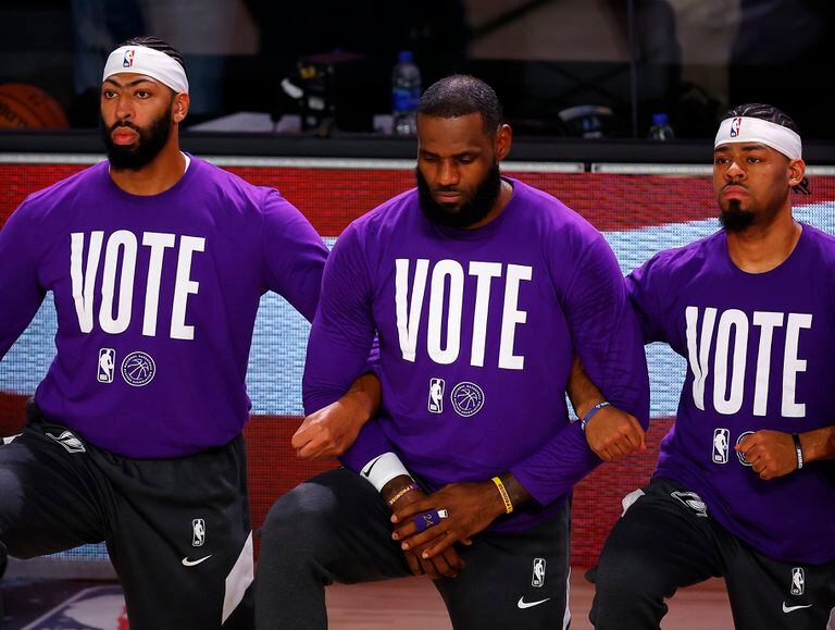 Anthony Davis, LeBron James e Quinn Cook, dos Lakers, com o lema “Vote” em suas camisetas.