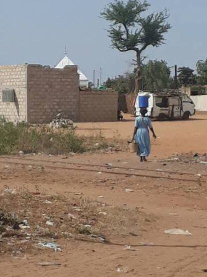 Mulher caminha com balde d'água na cabeça em Dahra, Senegal. 