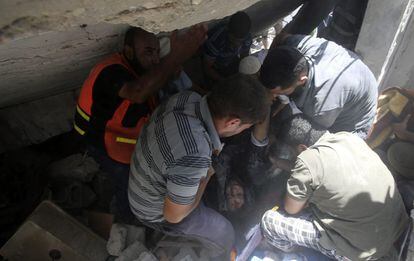 Uma equipe de resgate ajuda a retirar o corpo de uma mulher entre os escombros de sua casa em Gaza, em 30 de junho de 2014.