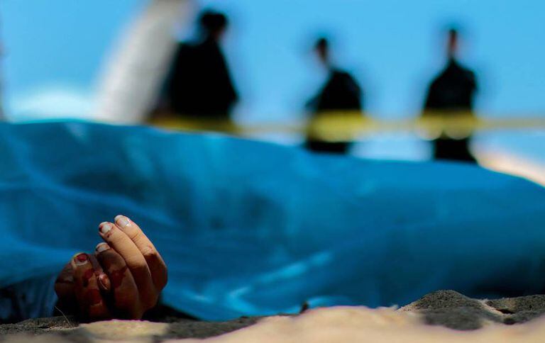 Peritos criminais observam o corpo de um homem morto em Acapulco em 2016.