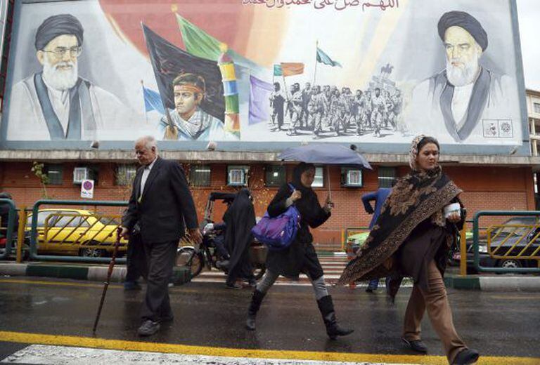 Pedestres passam por outdoor do líder supremo iraniano.