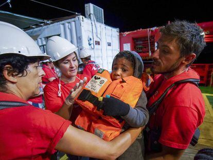 Trabalhadores de Save the Children ajudam uma criança que saiu da costa da Líbia em direção à Europa.
