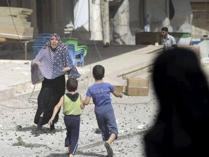 Mulher corre para pegar seus filhos após um bombardeio em Idlib, na Síria.