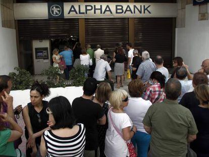 Atenienses fazem fila em frente a um caixa.