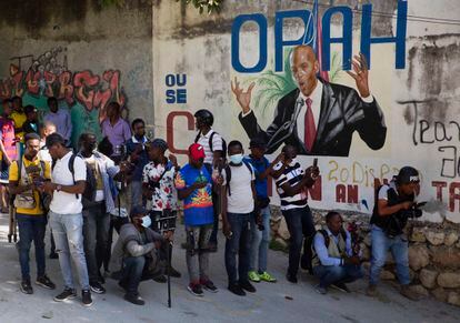 Um grupo de jornalistas se reúne em frente a um mural que mostra o presidente Jovenel Moïse perto da sua residência, onde ele foi assassinado a tiros na madrugada desta quarta-feira, 7 de julho.