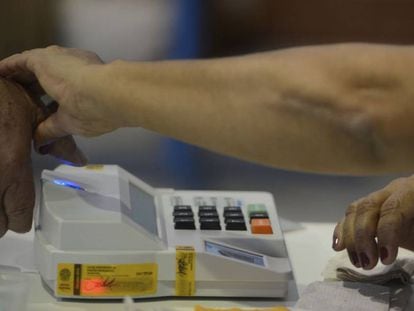 Mesária colhe digital de eleitor na eleição municipal de 2016 em Niterói.