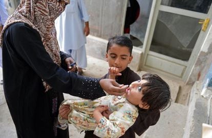 Uma trabalhadora paquistanesa vacina uma criança no Paquistão.