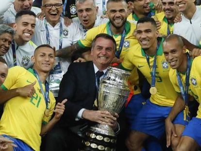 Bolsonaro posa com a taça ao lado dos jogadores da seleção.