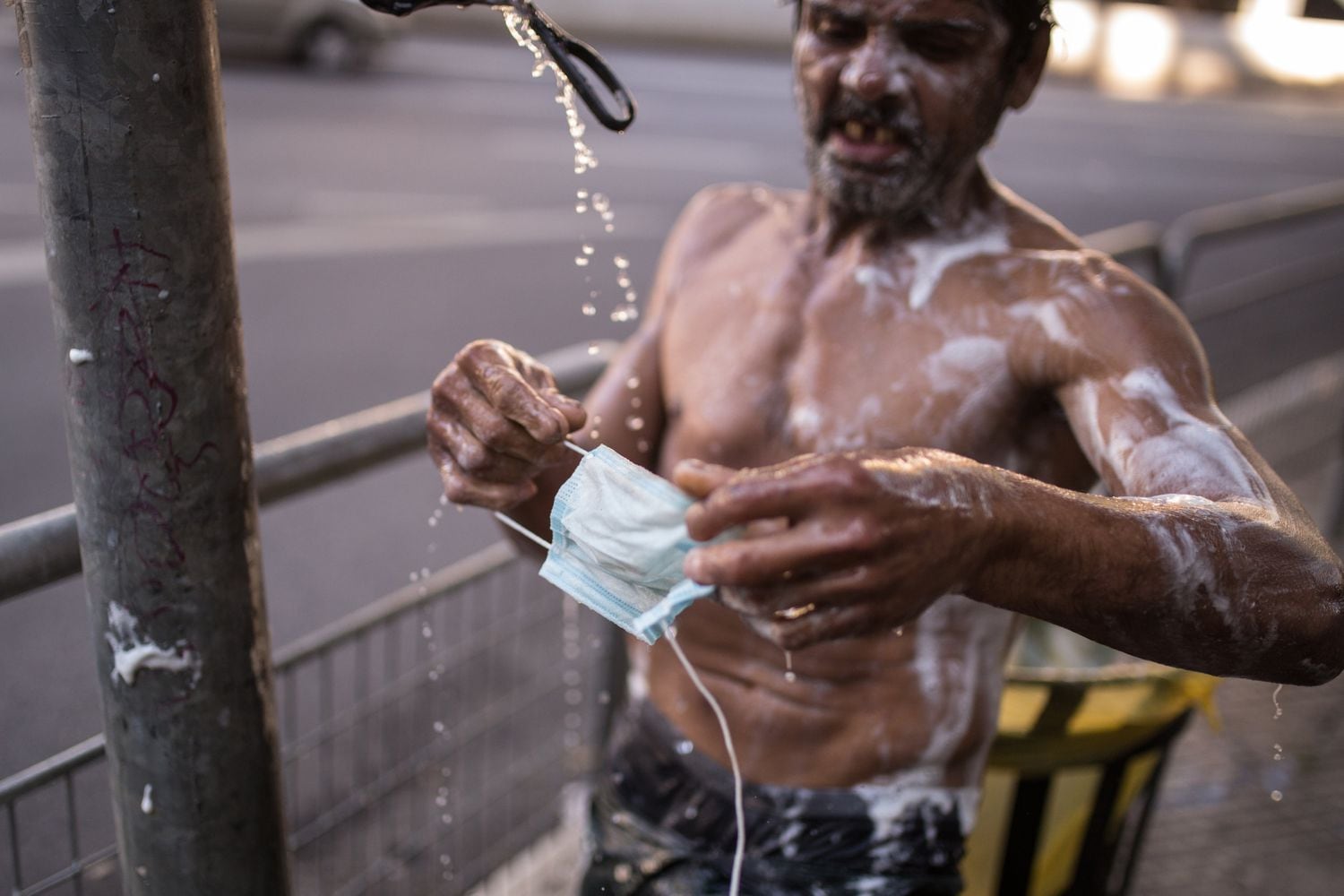 Morador de rua lava máscara em torneira improvisada em São Paulo, na última terça-feira.