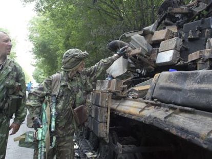 Militantes pró-russos observam os restos carbonizados de um tanque ucraniano perto de Donetsk.