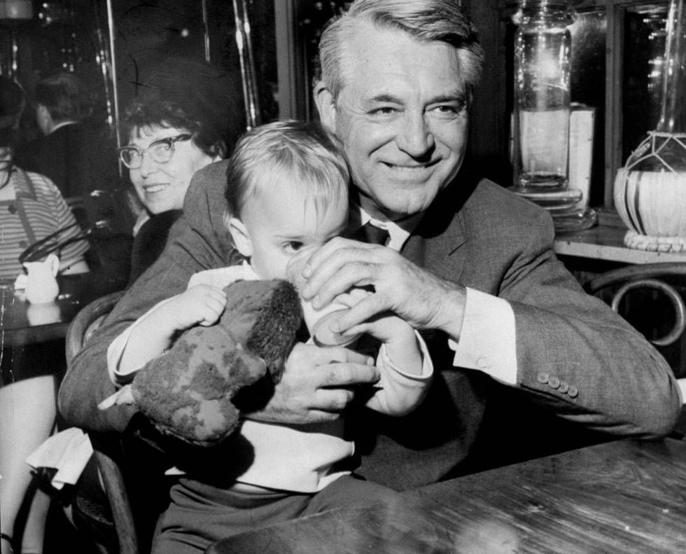Cary Grant com sua filha Jennifer Grant no colo, em um restaurante, em 1967.