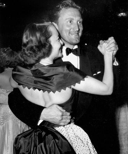 Quem iria dizer que Olivia de Havilland e Kirk Douglas, enquanto dançavam agarrados durante o Festival de Cannes de 1953 (na foto), 53 anos depois completariam 100 anos (ela, em 1 de julho) transformados nos últimos sobreviventes da Hollywood clássica. Ambos têm muito mais em comum que os anos de nascimento: os dois puseram Hollywood de joelhos e destruíram as fundações de uma indústria escravocrata com suas estrelas. Depois de seu primeiro trunfo como ator, Douglas se negou a assinar o contrato padrão de sete anos, pelo qual os atores eram obrigados a aceitar todos os projetos que o estúdio quisesse. Ele valorizava sua liberdade acima de tudo e revolucionou a indústria ao se tornar o primeiro astro a fundar a própria produtora. Olivia de Havilland também se rebelou contra o sistema quando levou a Warner à Justiça, cuja decisão resultou na “Lei De Havilland”, que pôs fim definitivamente à escravidão das estrelas.